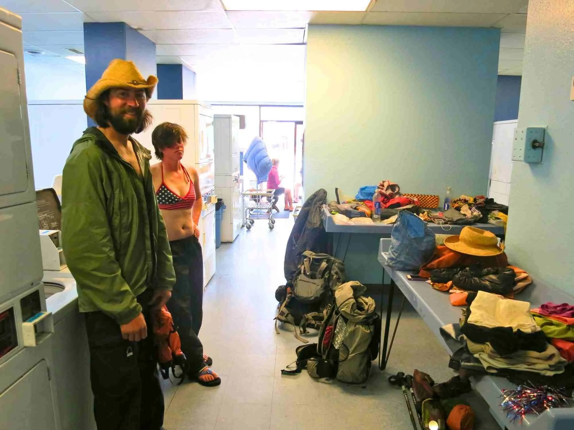 Outdoor enthusiasts sitting in a laundromat while washing their sleeping bags and technical jackets.