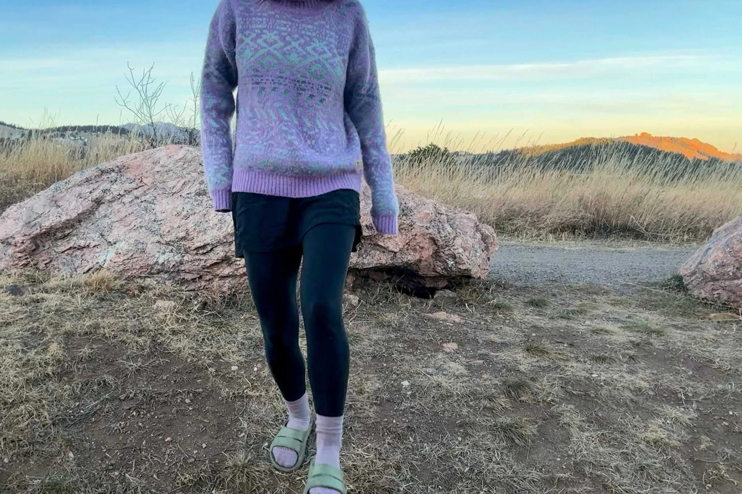 A person wearing OOFOS slides with thick wool socks outdoors.