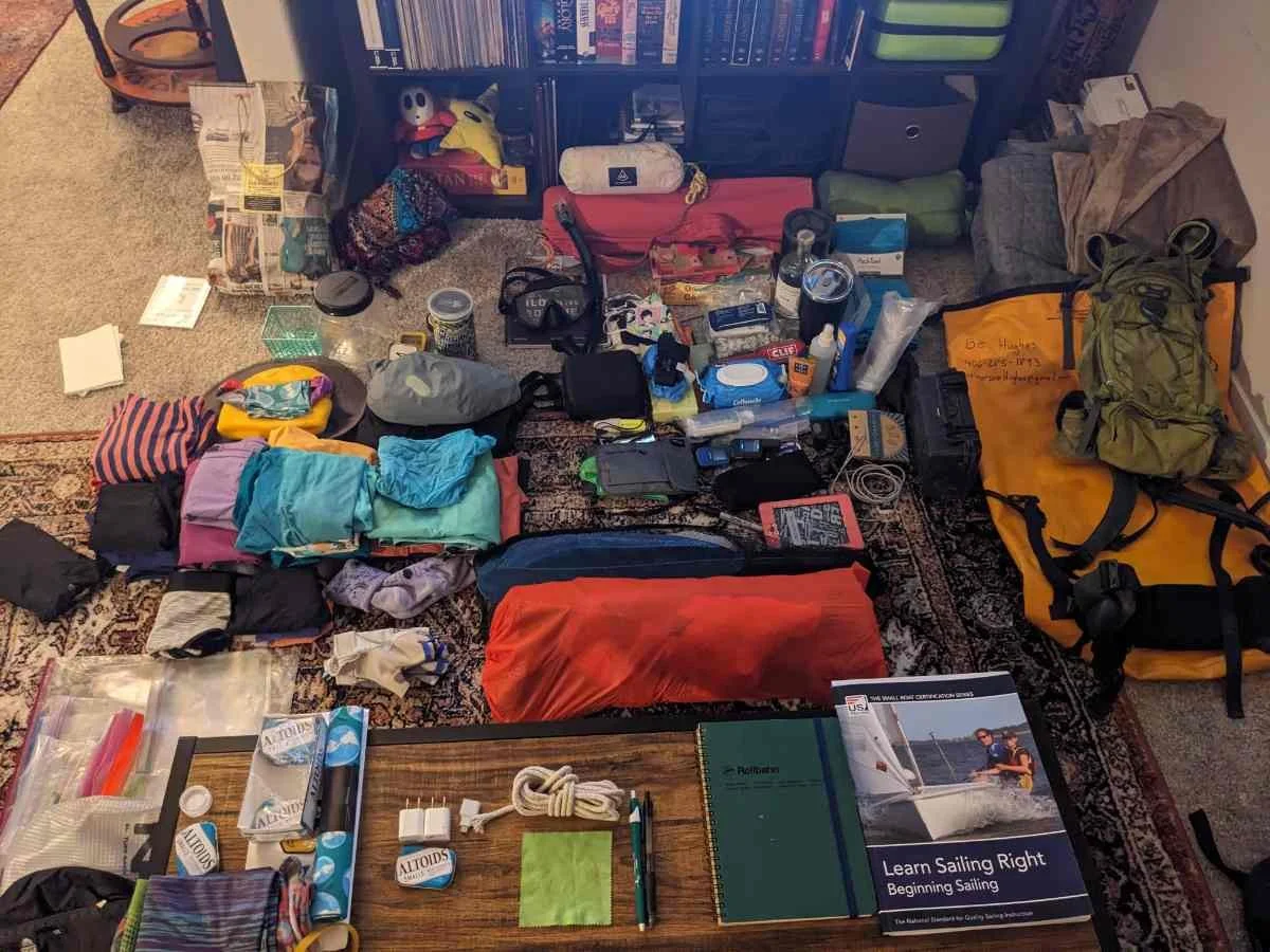 A flat-lay layout of hiking and travel gear spread out on the ground.