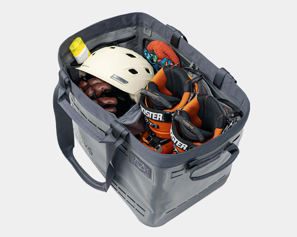 An open-top gear tote containing bulky outdoor apparel and equipment.